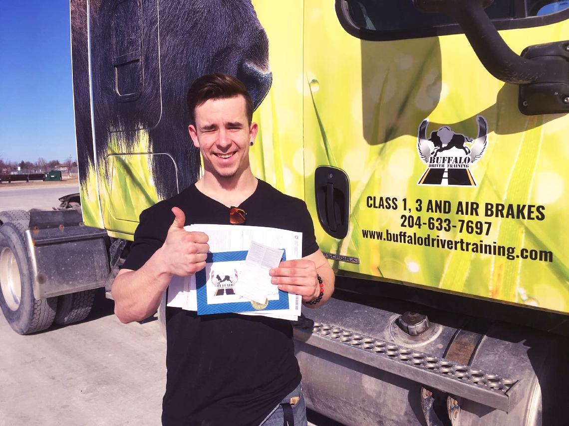 A Buffalo student celebrating a training milestone beside a branded truck
