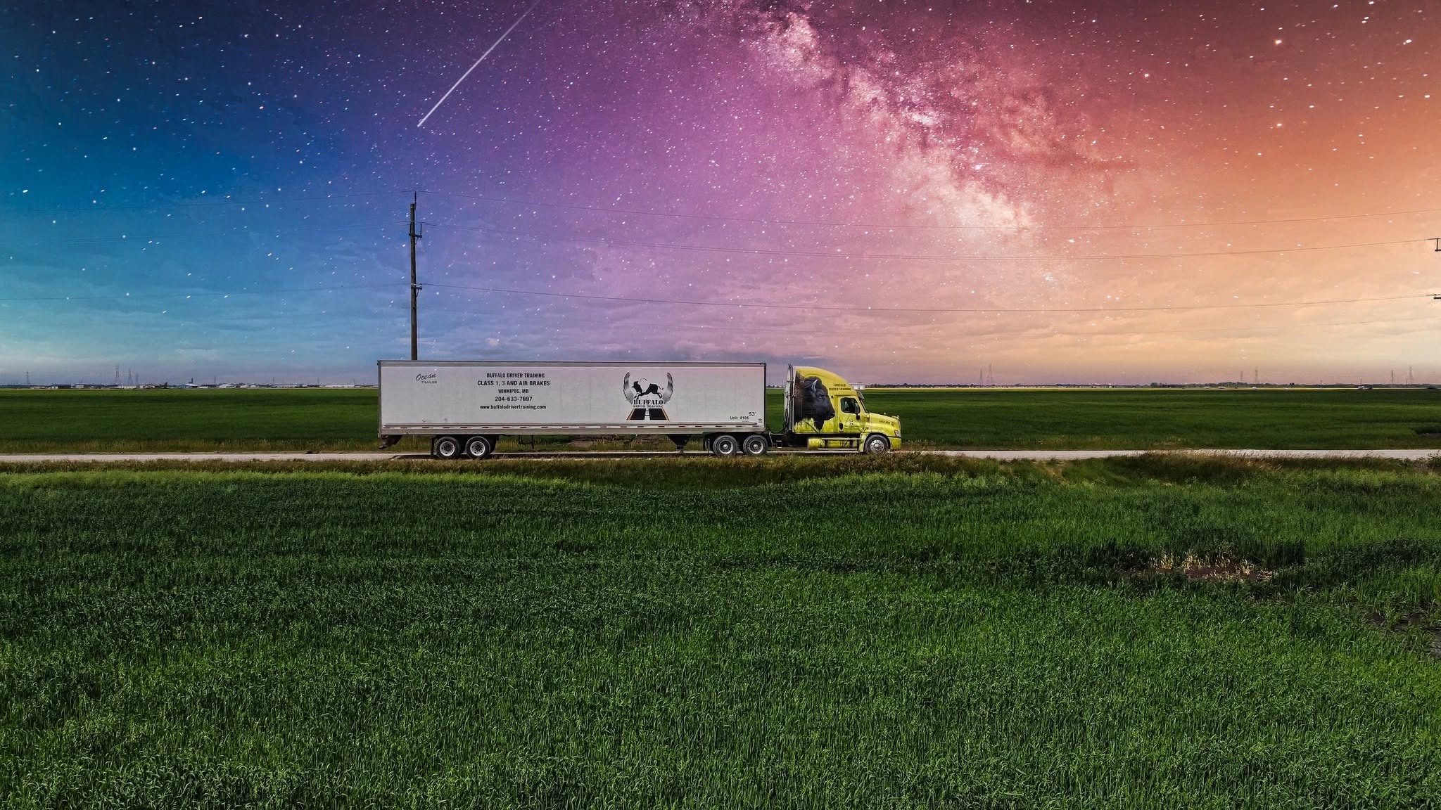 A Buffalo Driver Training truck on a prairie road beneath a colourful star-filled sky